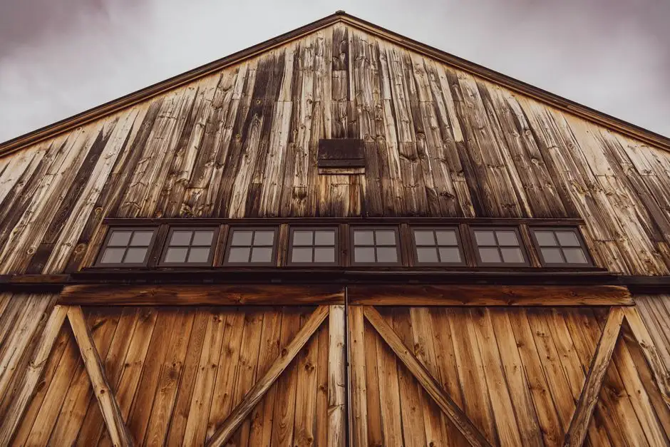 Capture of a rustic wooden barn with distinctive aged textures and large doors under a cloudy sky.